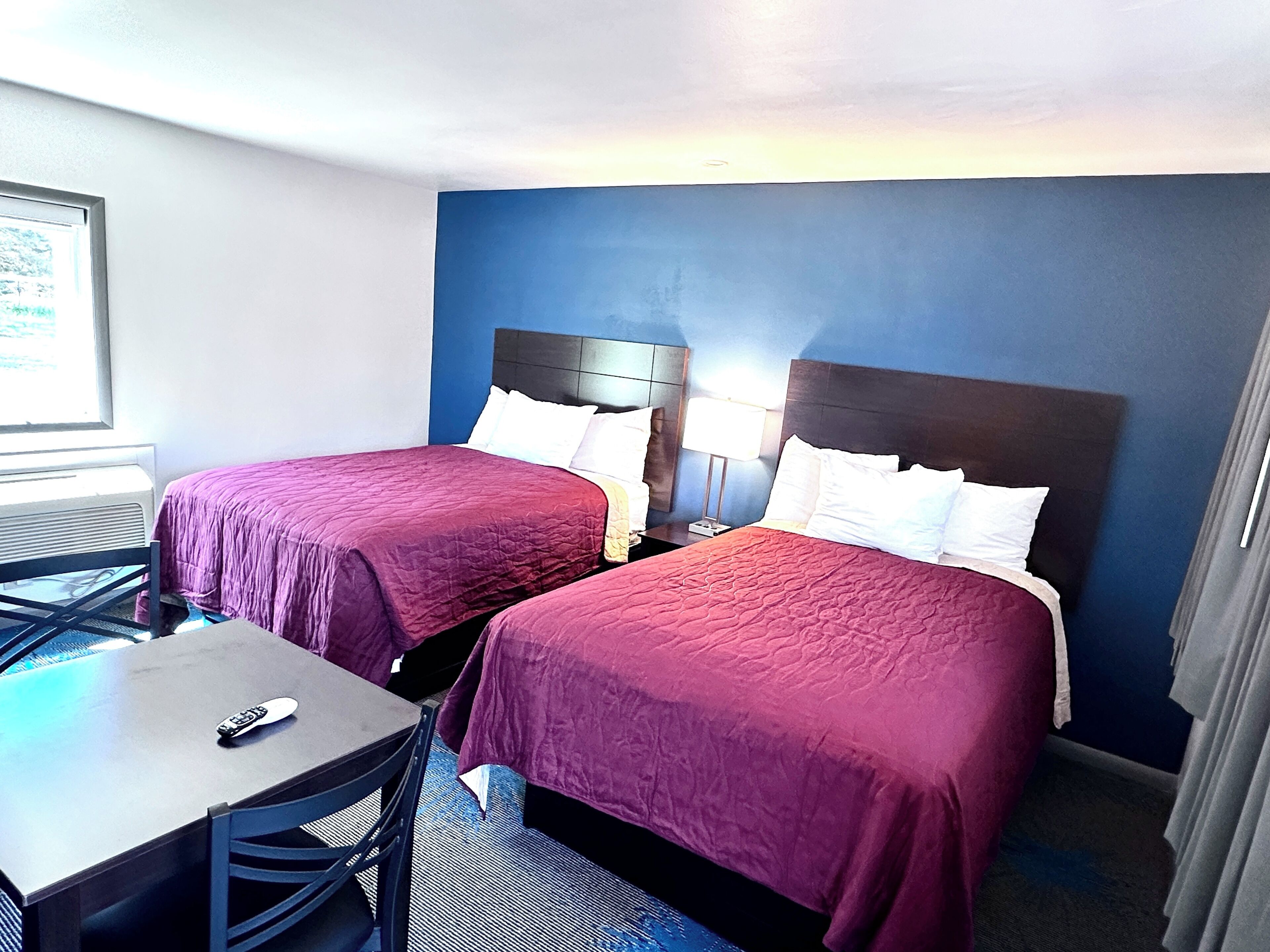 Habitación de hotel con dos camas, un escritorio y una silla.