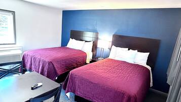 Quarto de hotel com duas camas, uma mesa e uma cadeira.
