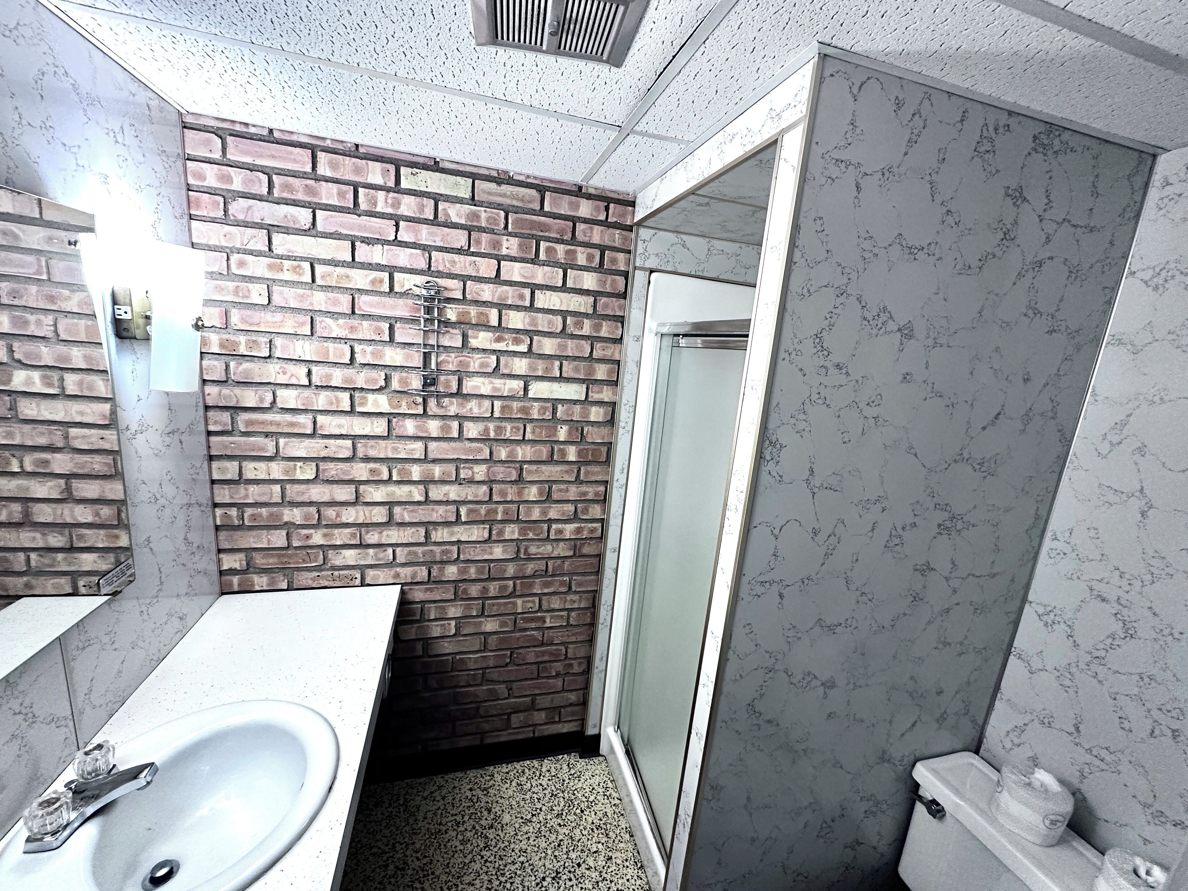 A bathroom with a white sink, a shower with a glass door, and a toilet.