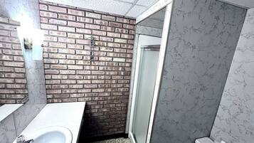 A bathroom with a white sink, a shower with a glass door, and a toilet.