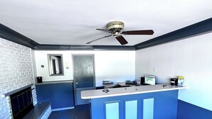 Una cocina con mostrador azul, ventilador de techo, puerta y chimenea.
