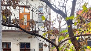 A courtyard with a wooden table and chairs, a metal fence, and potted plants. - GoodMo Budapest Smart Rooms (Budapest)