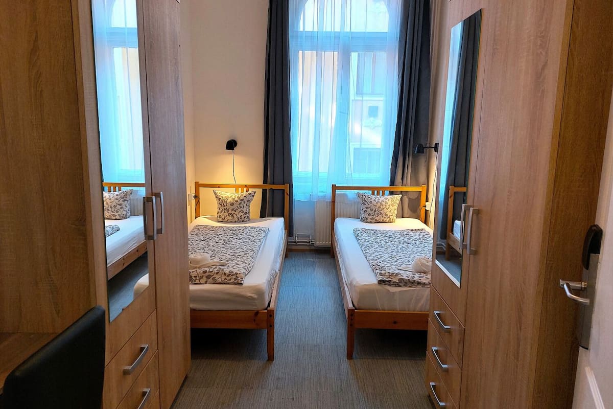 A room with two wooden beds, a small desk, and a mirror.