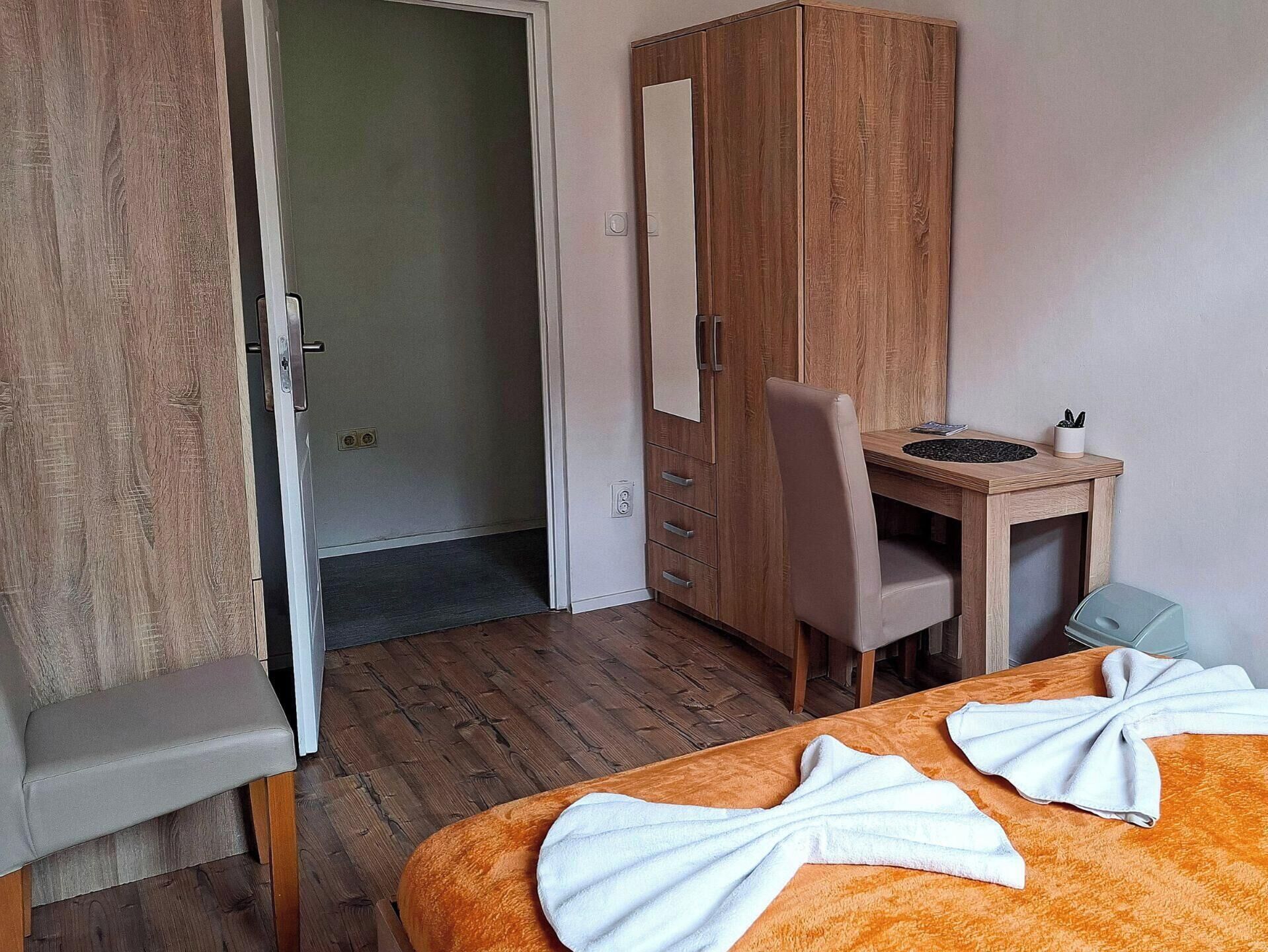 Une chambre d’hôtel avec une armoire en bois, un bureau avec une chaise et un lit avec des serviettes.