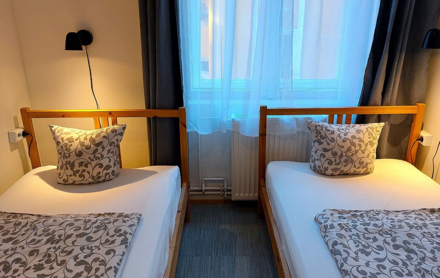 A double room with two beds, each with patterned pillows and a matching bedspread.
