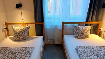 A double room with two beds, each with patterned pillows and a matching bedspread.