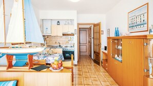 A kitchen with wooden cabinets, a stove, and a dining table with a sailboat model.