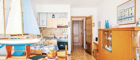 Una cocina con armarios de madera, una estufa y una mesa de comedor con un modelo de velero.