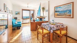 A dining area with a table set for two, a blue chair, and a wooden cabinet.