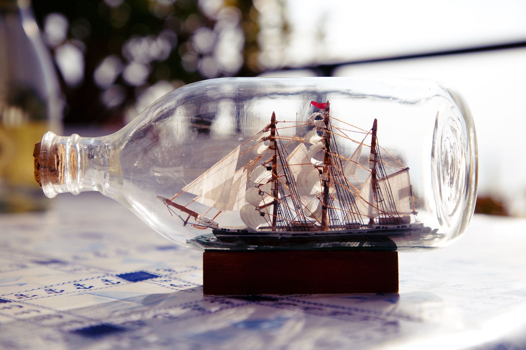 A ship model inside a clear bottle placed on a patterned surface.