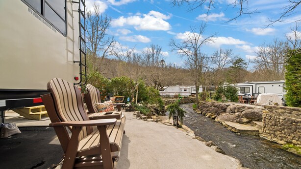 A campsite with RVs, a small stream, and picnic tables.