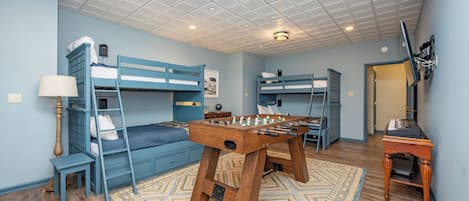 A room with bunk beds, a foosball table, and a desk with a computer.