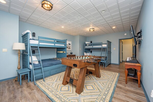 A room with bunk beds, a foosball table, and a desk with a computer.