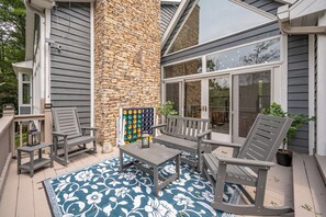 An outdoor patio with a stone wall, grey furniture, and a patterned rug.