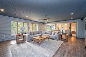 A spacious living room with a sectional sofa, a wooden coffee table, and a ceiling fan.