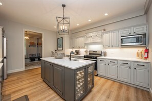 A modern kitchen with grey cabinets, a central island, and a stainless steel oven.