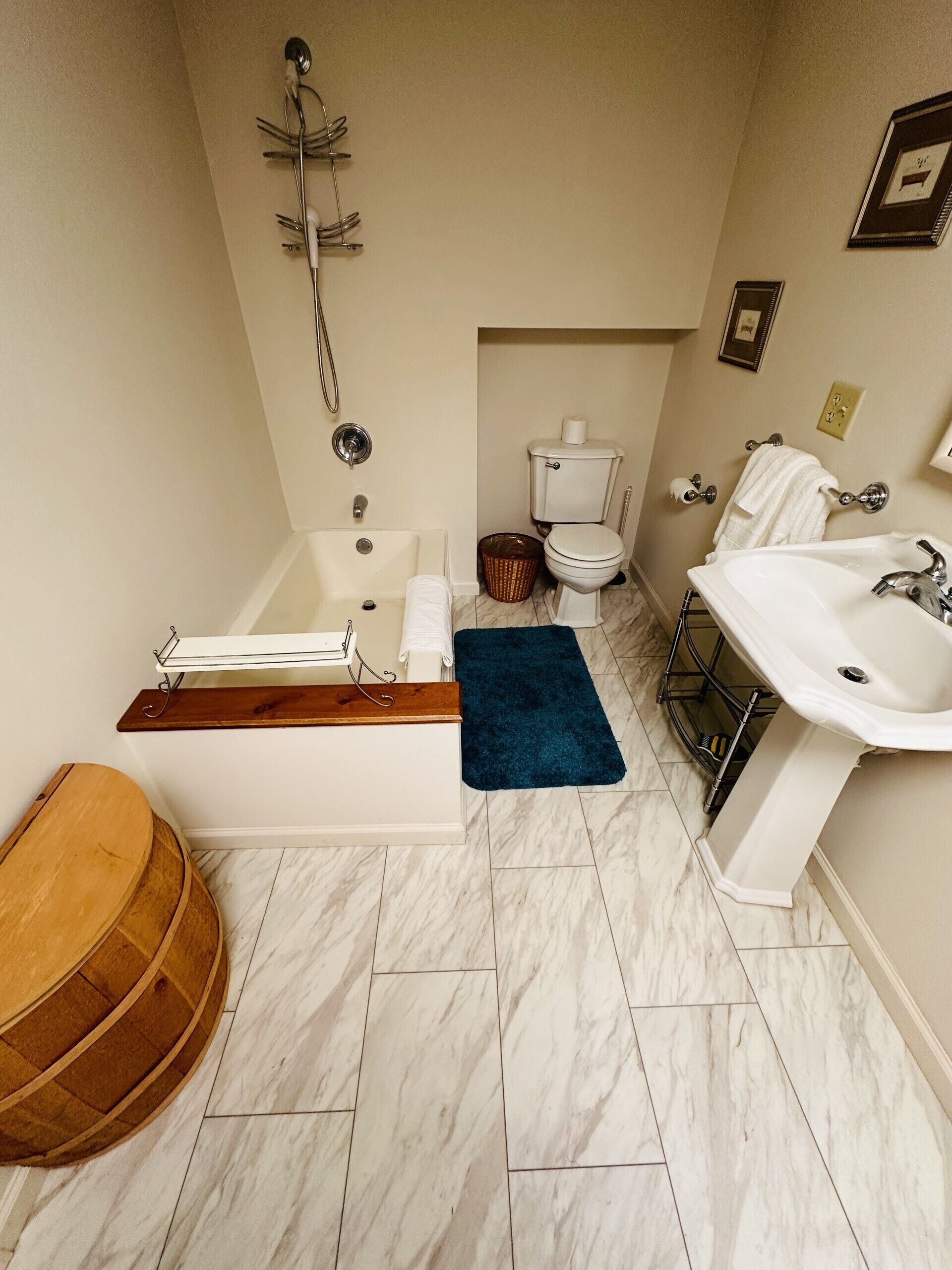 Un baño con bañera, inodoro, lavabo y un barril de madera.
