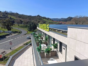 A hotel with a modern design, a rooftop solar panel installation, and a view of a winding road and hills. - B&B Hotel Castro Urdiales (Castro Urdiales)