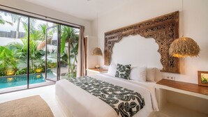Un dormitorio espacioso con una cama grande, vista a una piscina y un jardín tropical afuera.