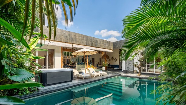 A modern outdoor pool area with lounge chairs and a covered seating area, surrounded by lush greenery. - Splendid Villa Shakti Canggu Boho chic 3bd & Pool (Canggu)