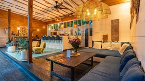 A spacious room with a wooden ceiling, a large woven light fixture, a sofa, a coffee table, and a view through large windows. - Splendid Villa Shakti Canggu Boho chic 3bd & Pool (Canggu)