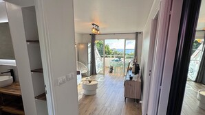 Amplia sala de estar con piso de madera, comedor con mesa y sillas, y balcón con vistas.