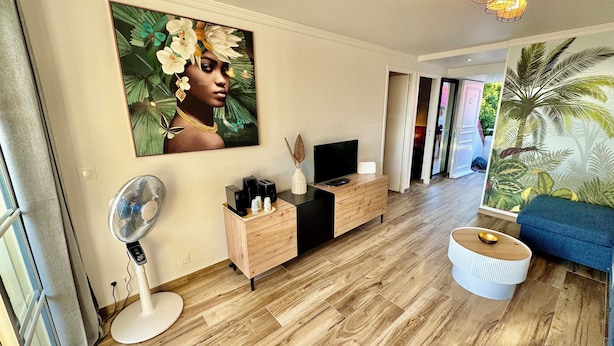 Una sala de estar moderna con un cuadro grande, muebles de madera, un televisor y un ventilador.