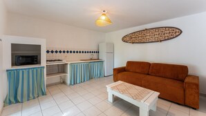 A compact living space with a kitchenette, a sofa, and a patterned table. - Villa Chill & Ride Le Helleux Magnifique Piscine (Sainte-Anne)