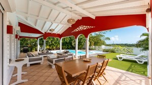 A covered outdoor area with a pool, seating, and a dining table. - Villa Chill & Ride Le Helleux Magnifique Piscine (Sainte-Anne)