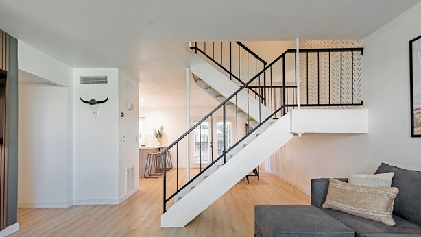 Ein modernes Wohnzimmer mit Treppe, einem grauen Sofa und einem Wandbild.