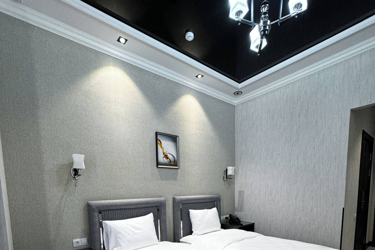 A hotel room with a large bed, bedside tables, a wall-mounted light fixture, and a framed picture.