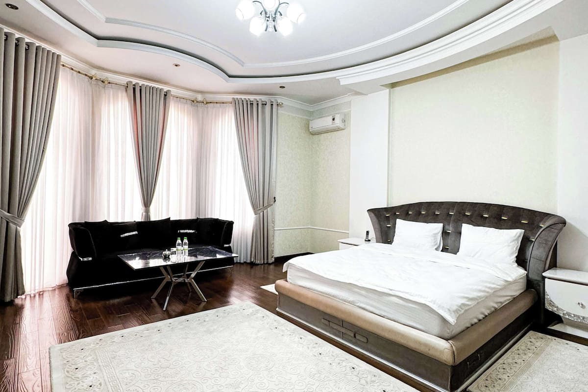 A bedroom with a large bed, a desk, and a chandelier.