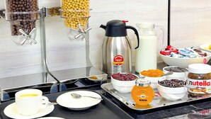 A breakfast buffet setup with various food items and a coffee machine. - De Villa Hotel (Samarkand)