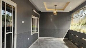 Une pièce spacieuse dotée d’un sol en marbre, d’un luminaire au plafond et d’une fenêtre ornée d’une grille métallique.