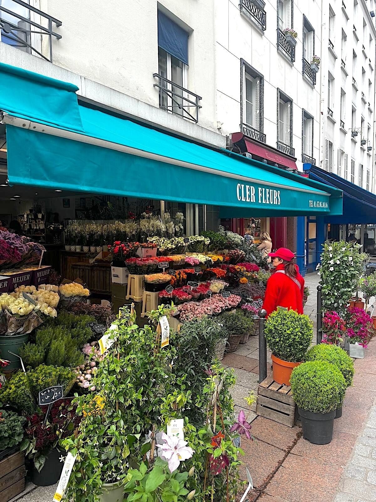 Una floristería llamada 'Clever Flowers' exhibe una variedad de flores y plantas en su escaparate.