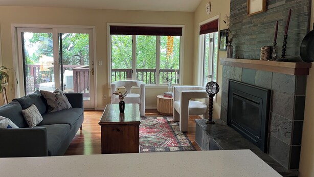 A living room with a fireplace, a sofa, a coffee table, and a view of the outdoors. - Beautiful family home in the Upper Rattlesnake (Missoula)