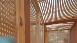 Une structure en bois ornée d’un motif en treillis, qui pourrait être un balcon ou une partie de la façade d’un bâtiment.