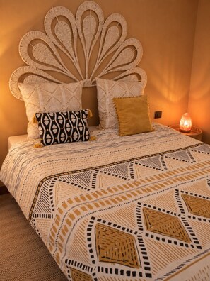 A bed with a patterned bedspread and a decorative headboard.