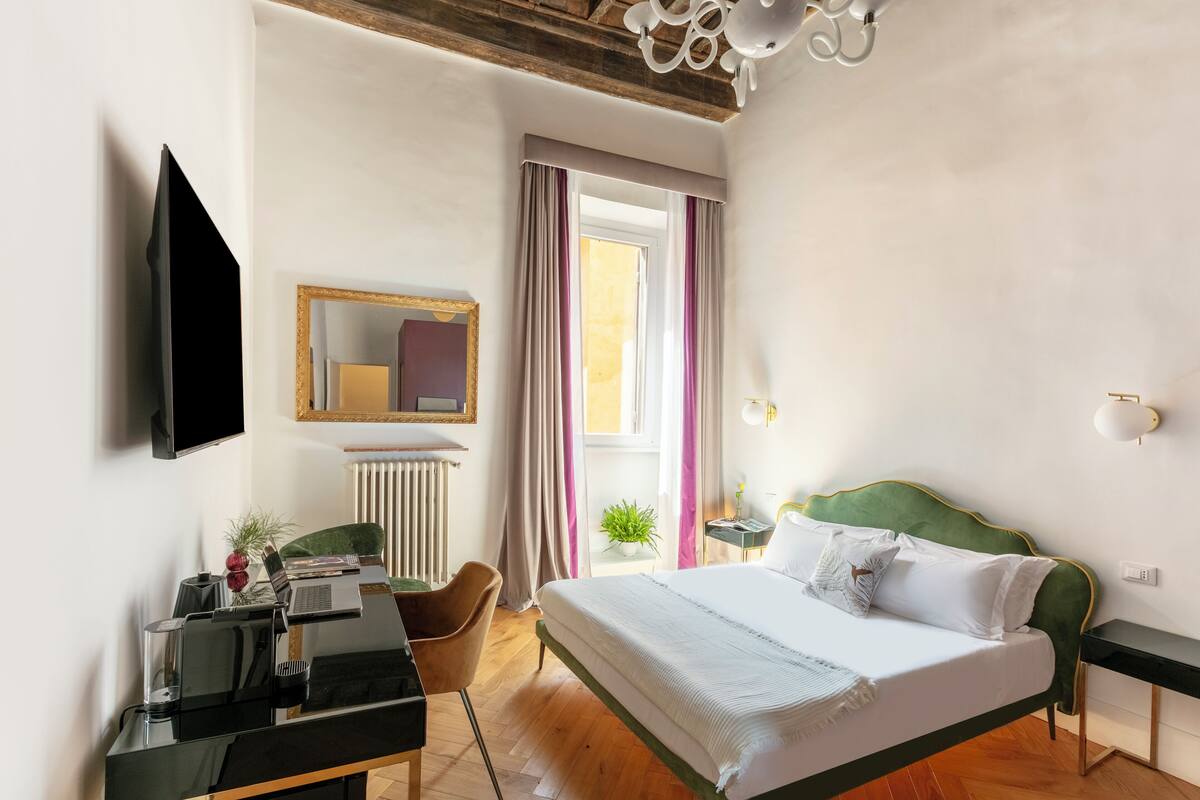 A modern hotel room with a bed, desk, chair, and a television.
