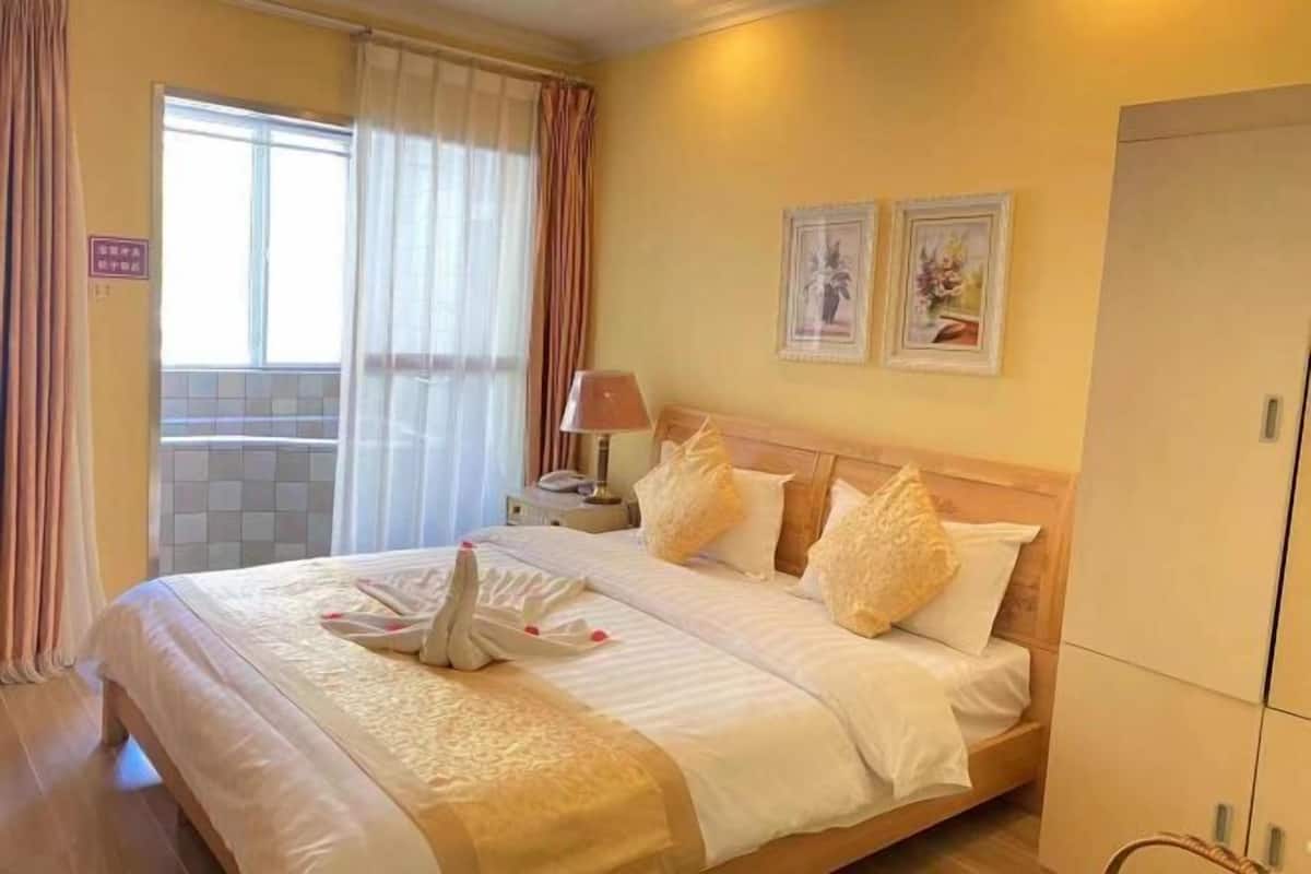 A hotel room with a bed, a nightstand, a lamp, and two framed pictures on the wall.