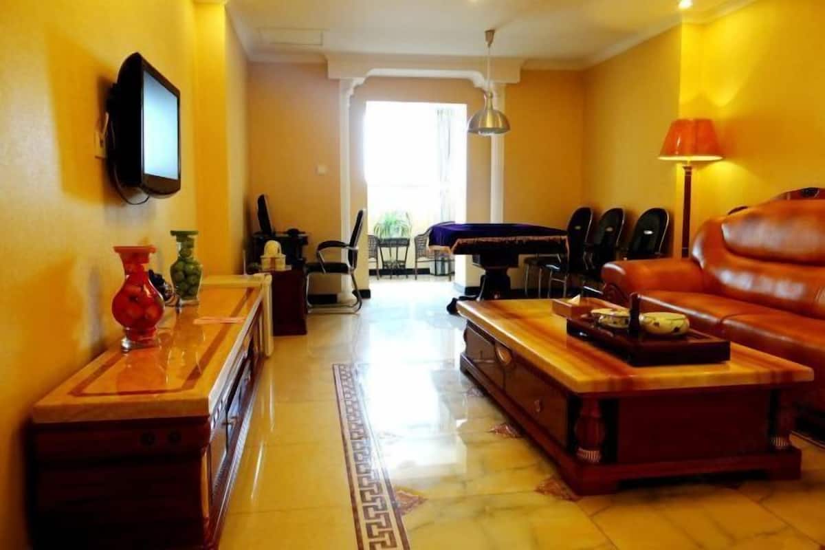 A living room with a television, a sofa, a coffee table, and a dining area with chairs.