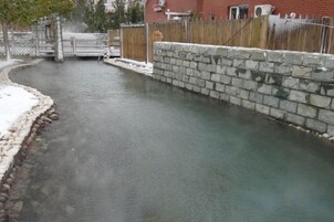 Un estrecho canal de agua con un muro de piedra a un lado y una valla de madera al otro.