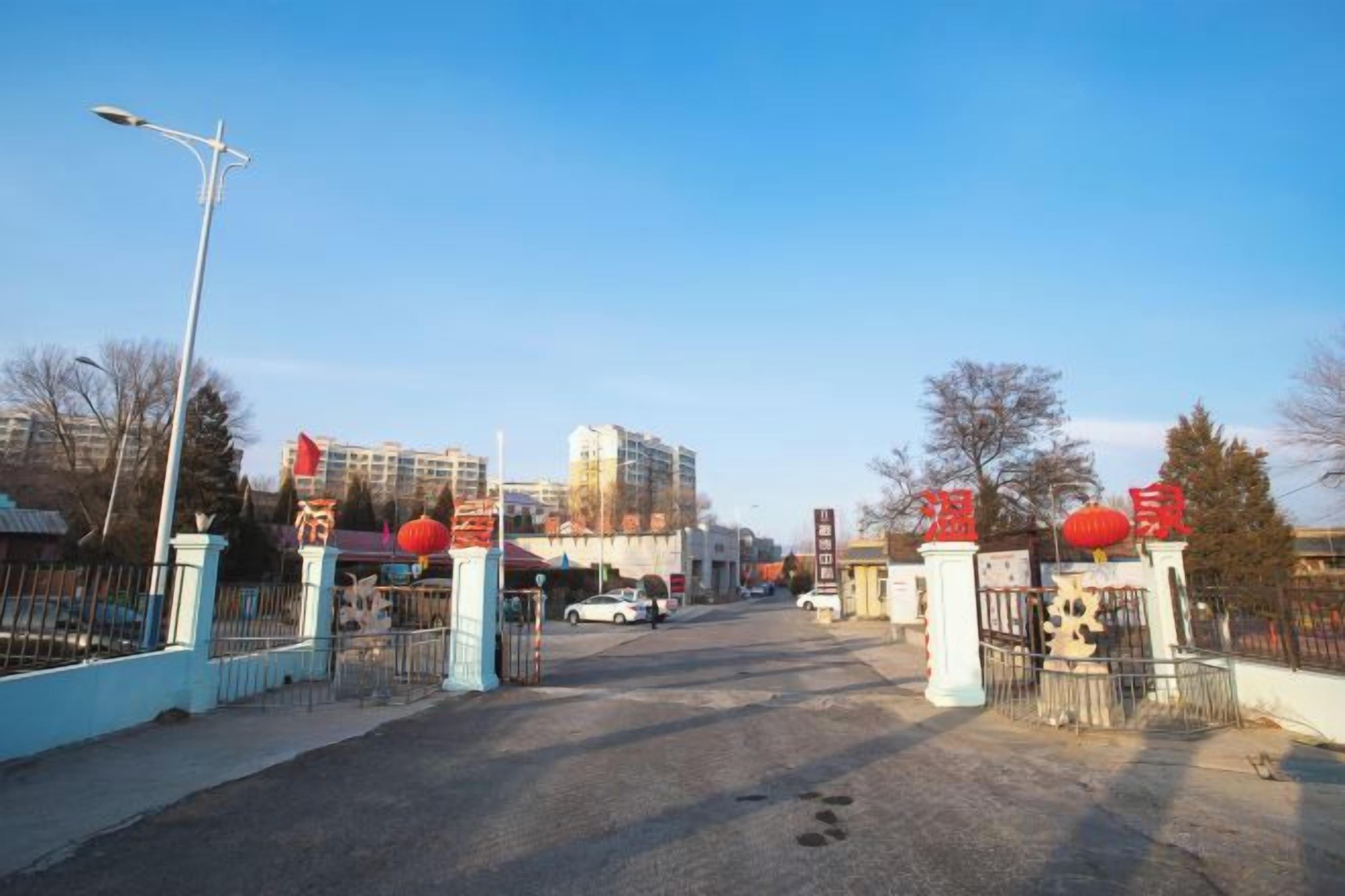 A gated entrance with a streetlight, a clear sky, and buildings in the background.