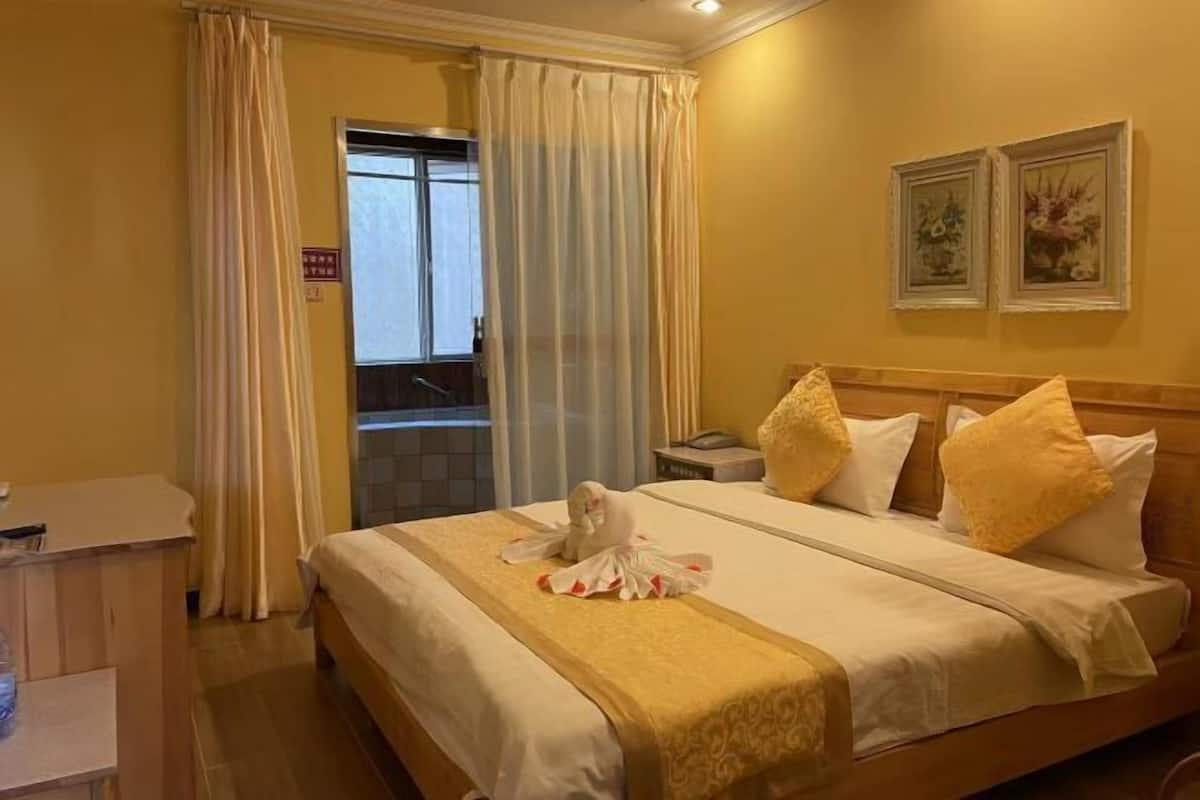 A hotel room with a bed, a desk, and a window with curtains.