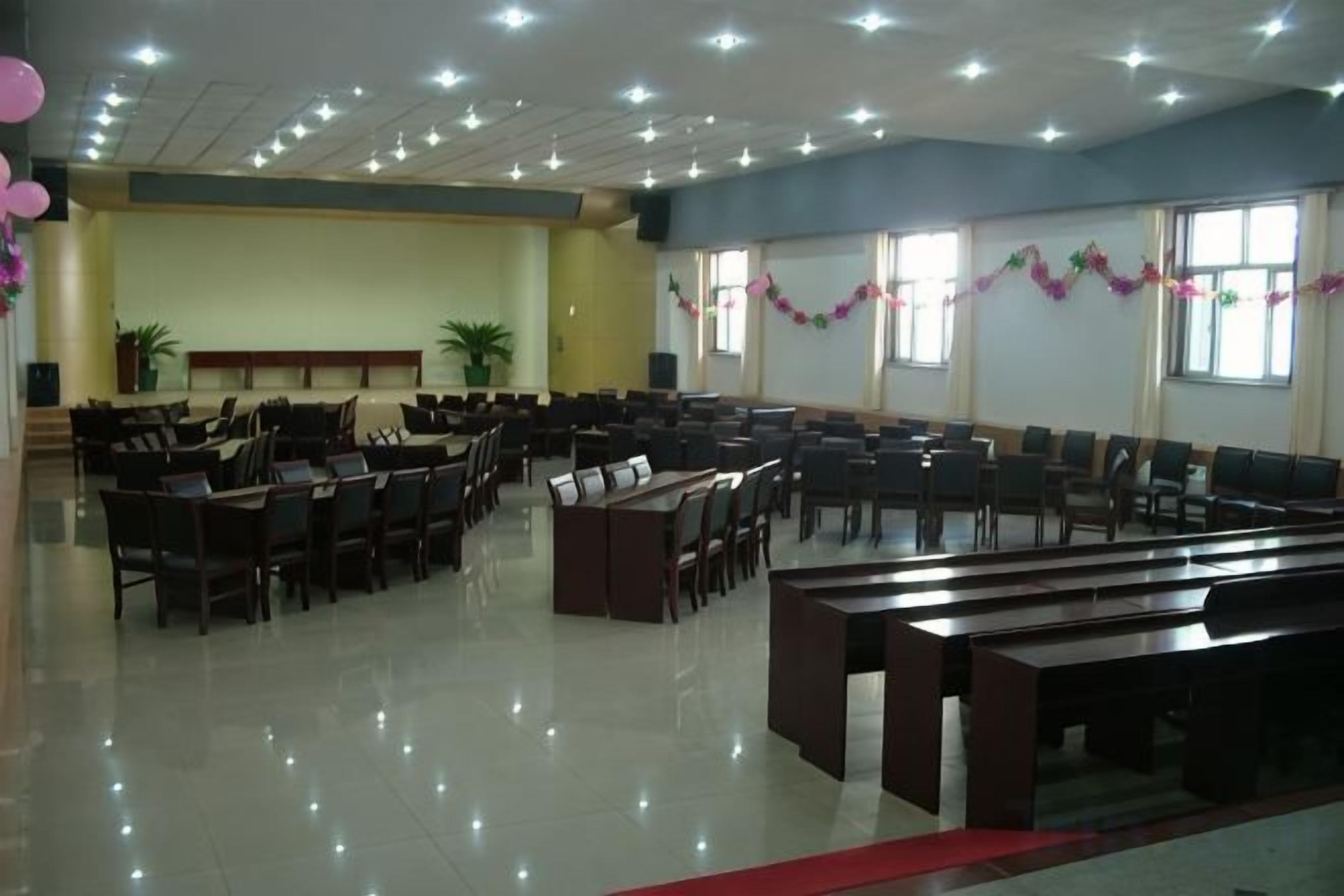 Un salón amplio con filas de sillas y mesas, presumiblemente para un evento o reunión.