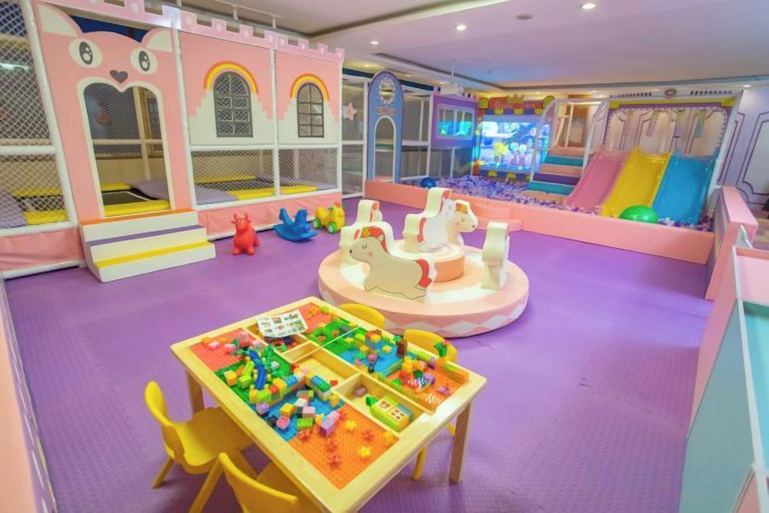A children's play area with a ball pit, play structures, and a table with building blocks.
