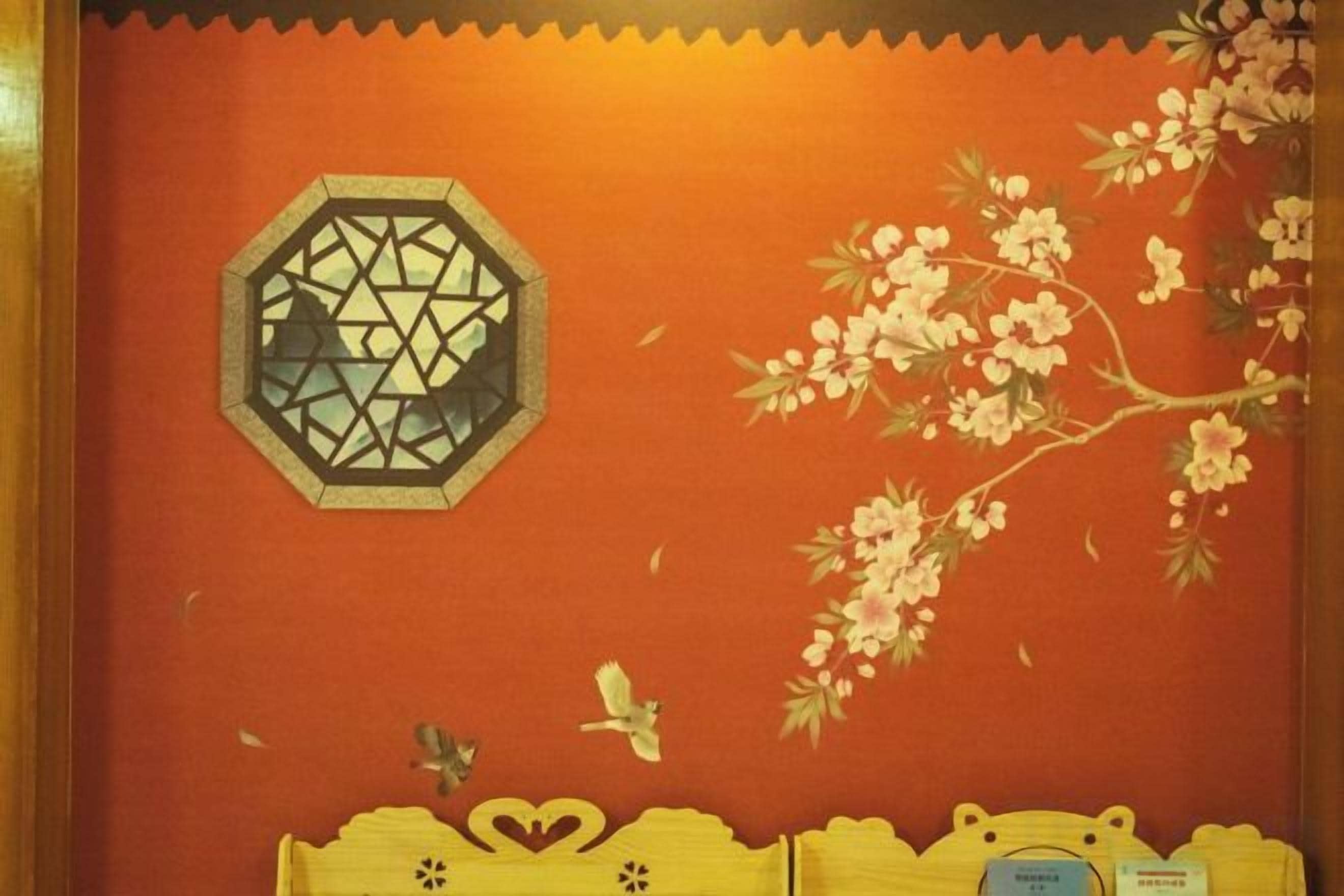 A room with a red wall, a geometric window design, and a floral pattern.