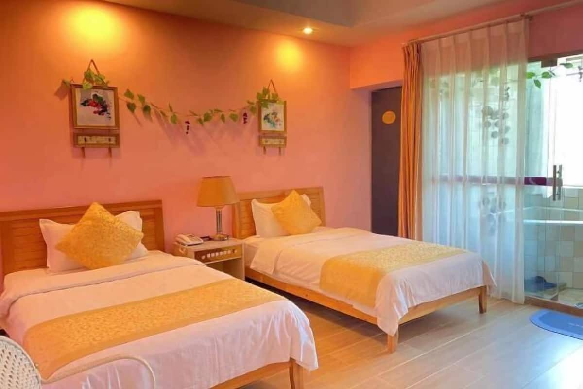 A hotel room with two beds, a nightstand with a lamp, a wall-mounted clock, and a window with curtains.