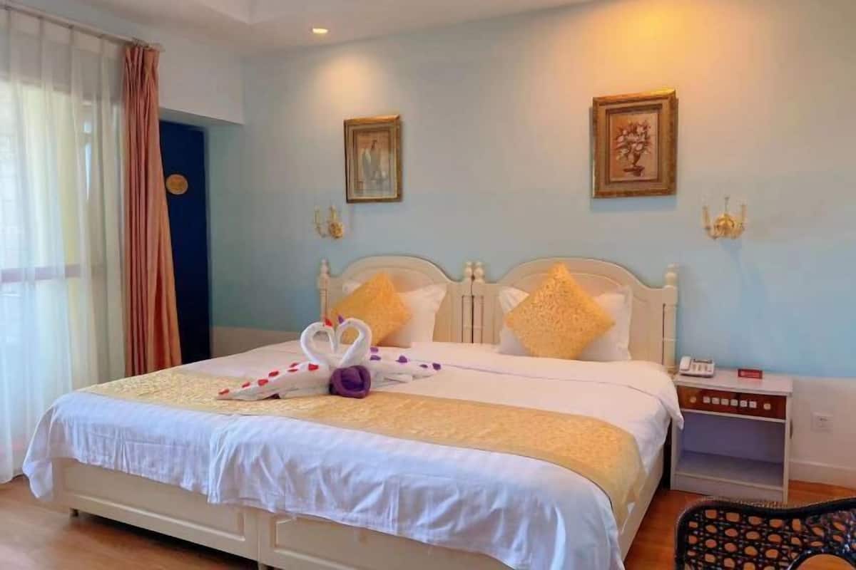 A hotel room with a bed, a nightstand, a chair, and a window with curtains.