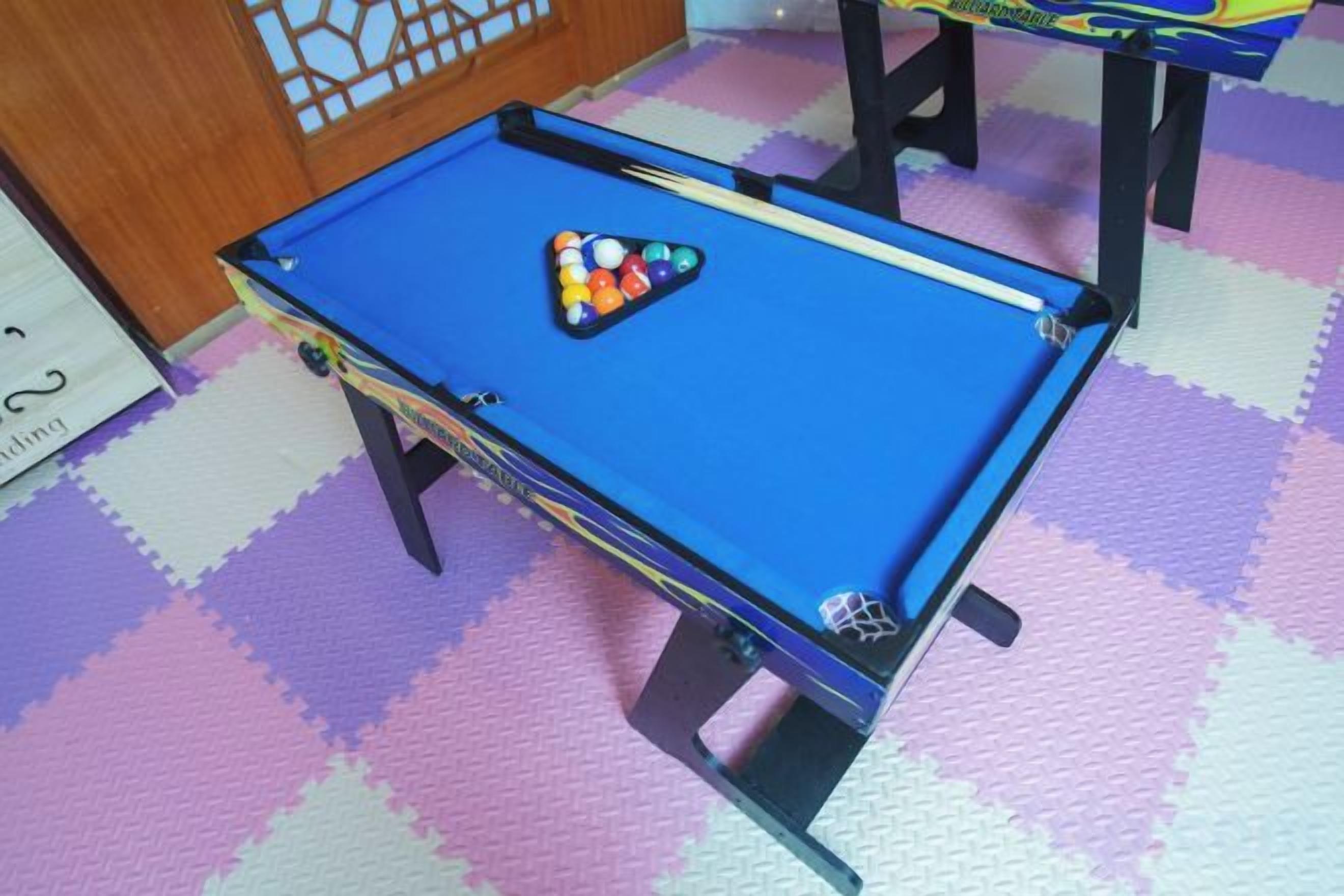 A pool table with balls on it, placed on a checkered floor.